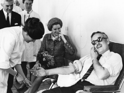 Princess Grace looks on as Prince Rainier donates blood in 1968.