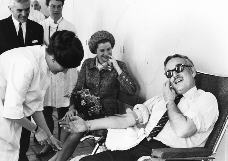Princess Grace looks on as Prince Rainier donates blood in 1968.